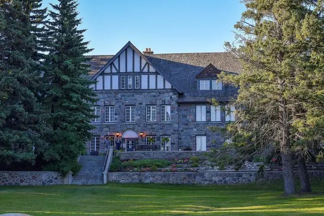 Stone lodge building with gardens and lawn